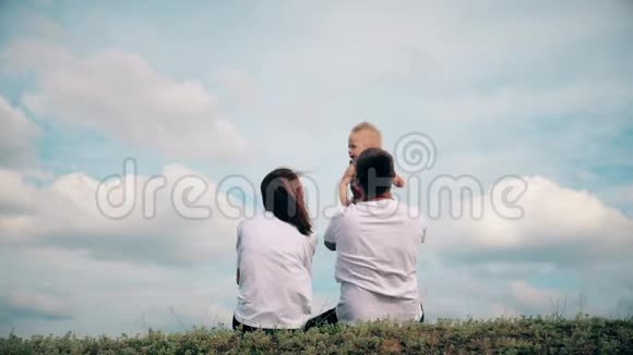 幸福的家庭在一片背景云天的草地上视频的预览图