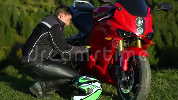 一个骑摩托车的人带着摩托车在山上的年轻帅哥他坐在摩托车旁边视频的预览图