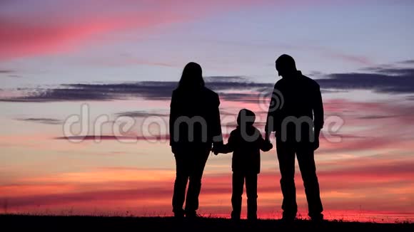 日落时的家庭剪影肖像父母和孩子牵手无敌视频的预览图