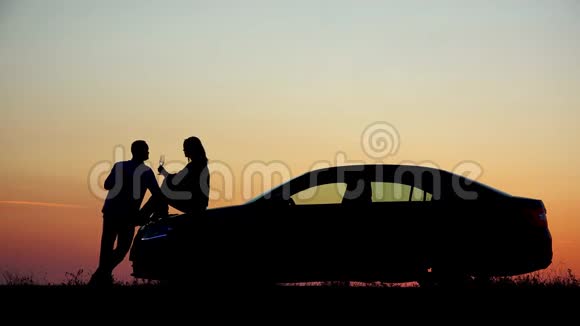 情侣剪影喝香槟日落女人坐在车上浪漫视频的预览图