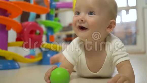 快乐有趣的婴儿手里拿着彩色球试图爬得紧紧的视频的预览图