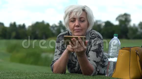 躺在割草上看手机的女人视频的预览图