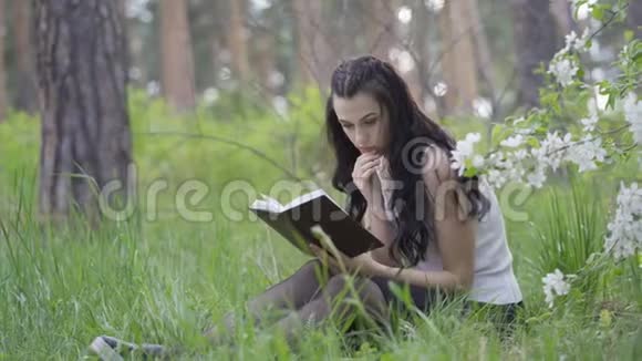 4K年轻女子坐在公园里看书视频的预览图