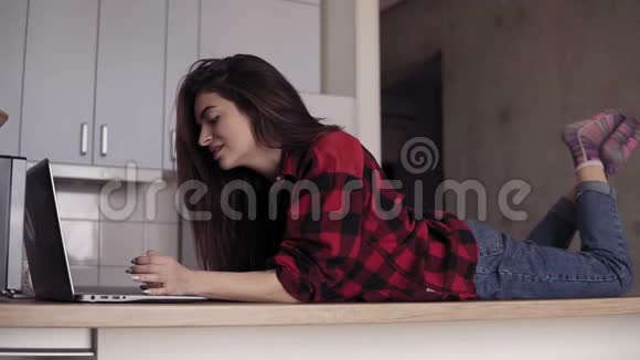 一个20的女孩躺在厨房的桌子上用笔记本电脑打字视频的预览图