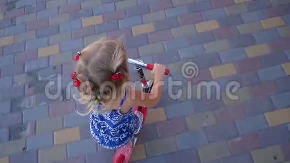 一个金发小女孩很快就骑着滑板车城市背景视频的预览图