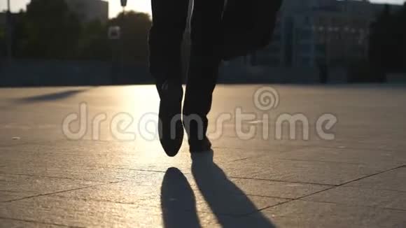 一个年轻的商人的脚带着一个公文包走在城市的街道上商务人员上下班穿西装的自信男人视频的预览图