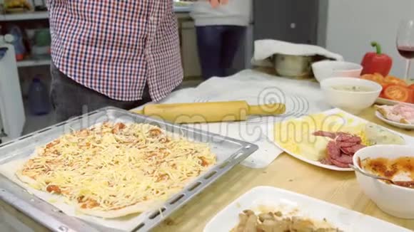 年轻的家庭在厨房一起做意大利香肠披萨双手特写视频的预览图