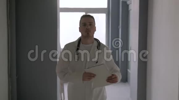 一位带着听诊器的医生穿过医院的走廊视频的预览图