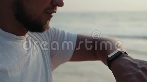 活跃的生活方式男人游客看科技智能手表特写宏观特写手臂海滩触摸屏手腕上视频的预览图