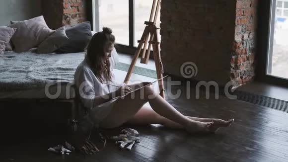 坐在家里画室地板上的女艺术家作品视频的预览图