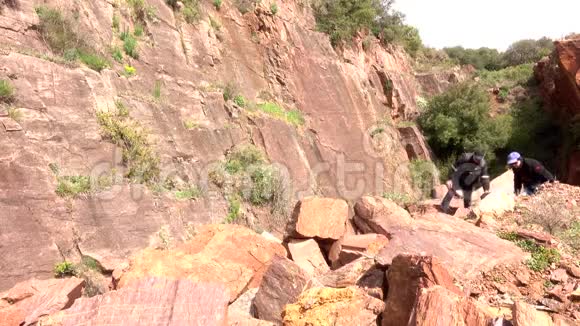 一个成年男人和女人爬上堆积如山的石头视频的预览图