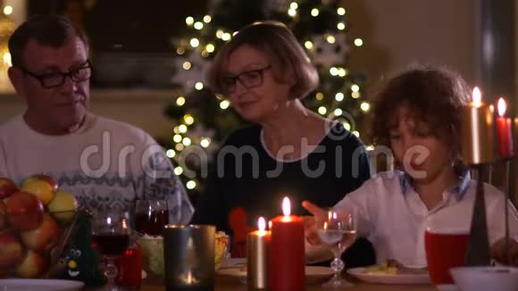 祖父和祖母坐在节日的桌子旁喝着红酒圣诞祝词圣诞祝福视频的预览图