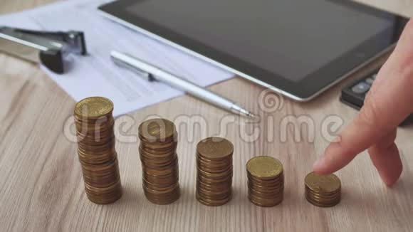 人手捧钱币在钱币堆上排列成木桌上的图形男性或女性手指的手视频的预览图