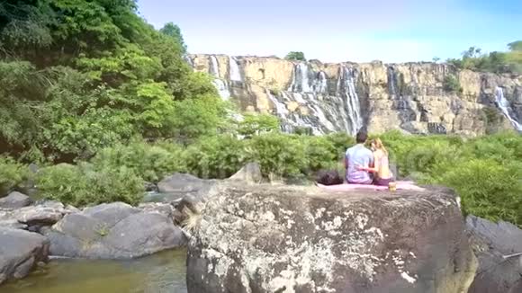 后面的女孩拥抱男人石头对瀑布视频的预览图