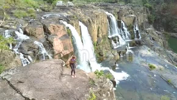 女孩赤脚坐在瀑布般的岩石上视频的预览图
