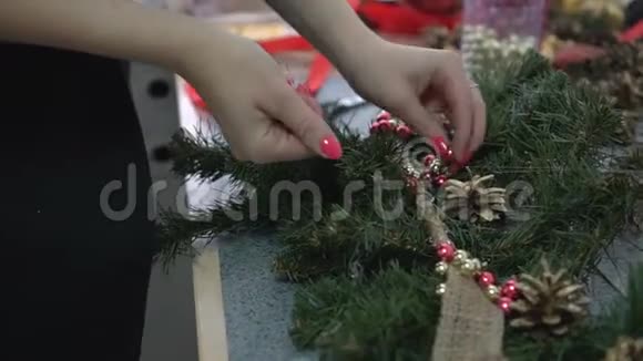 女人用闪亮的珠子和松果装饰手工制作的圣诞树枝视频的预览图