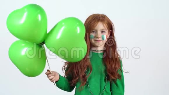 小女孩在白色的墙上举着四叶草形状气球庆祝圣帕特里克节视频的预览图