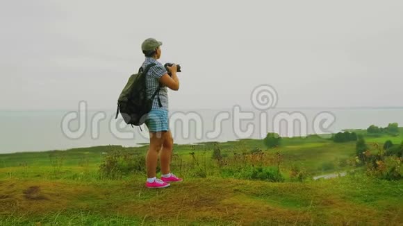 一个背着背包的女人在山上拍了一张湖的照片视频的预览图