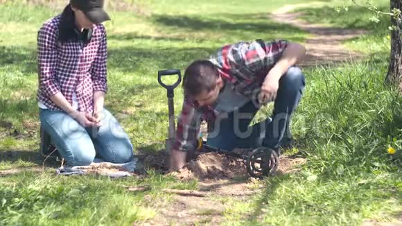 男女寻宝者用金属探测器挖掘公园里发现的旧硬币视频的预览图