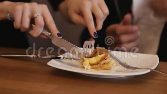 年轻夫妇一起吃蛋糕女性用叉子和刀在白色盘子上切蛋糕视频的预览图