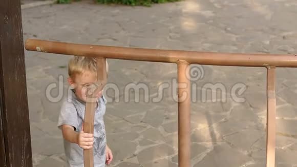 小男孩爬上公园凉亭的篱笆视频的预览图