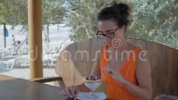 戴眼镜的美女坐在海边的咖啡馆里吃甜点视频的预览图