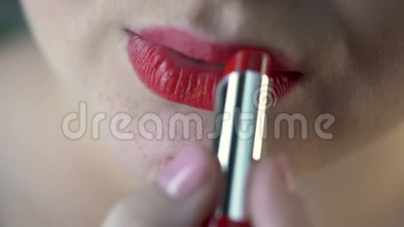 丰满的女人在相机前涂上红色口红化妆和美容特写视频的预览图