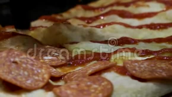 用黑色的烹饪手套把意大利腊肠切片放在带有番茄酱的比萨饼基地上这是烹饪理念视频的预览图