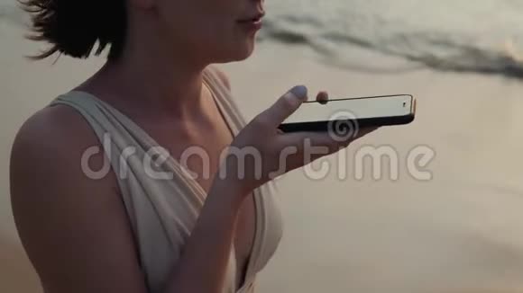 女青年游客在日落时分使用手机智能手机语音信息语音识别应用视频的预览图