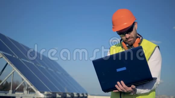 工人类型在他的笔记本电脑站在旁边的阳光面板在大楼4K视频的预览图