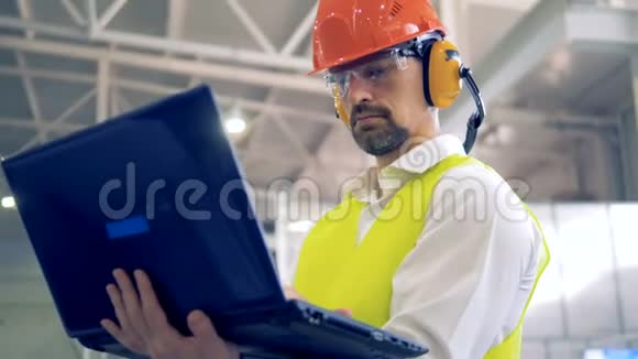 工厂的员工站着用他的笔记本电脑工作视频的预览图