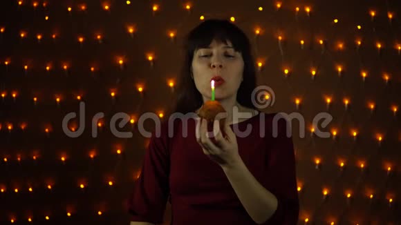 一个年轻的女人吹灭蜡烛咬他的生日蛋糕视频的预览图