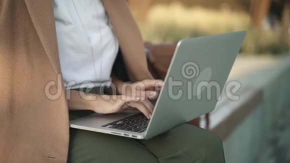 秋天公园的女人手在笔记本电脑键盘上打字视频的预览图