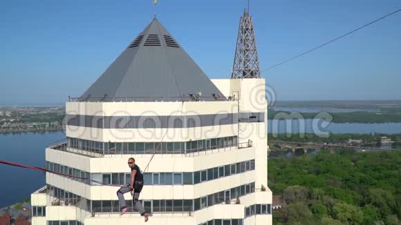 一个人坐在两座摩天大楼之间的绳子上高高的视频的预览图