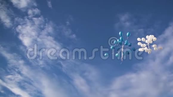 白色和蓝色的气球被释放出来在蓝天上高高飞翔视频的预览图