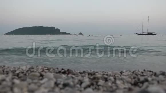 海浪在石岩海滩上冲浪游艇和岛屿的背景视频的预览图
