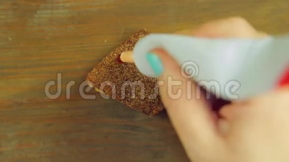 一只手拿着一管烹饪颜料在巧克力饼干上画着带有红色油漆的滑稽杯子手工制作视频的预览图