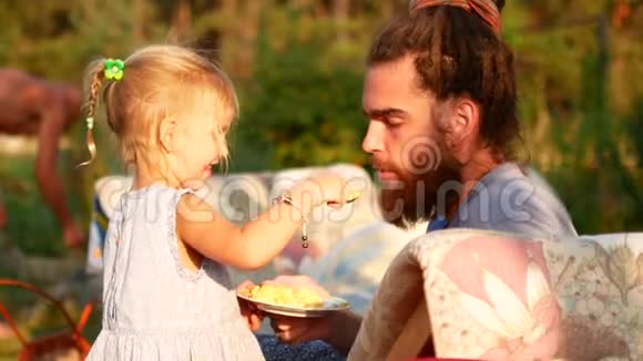 一个小女孩用勺子喂她爸爸夏天晚上在村里视频的预览图