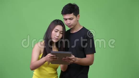 年轻的亚洲夫妇使用数码平板电脑看起来很惊讶视频的预览图
