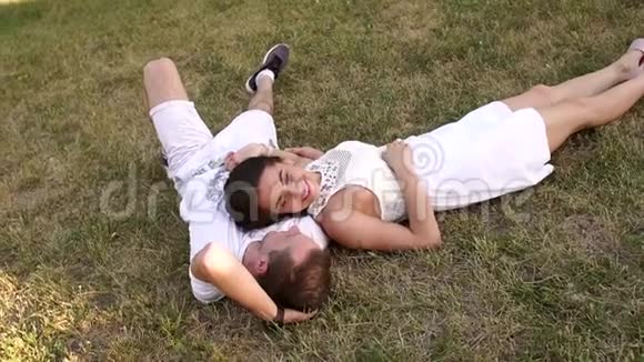 美丽的夫妇躺在公园的草地上视频的预览图