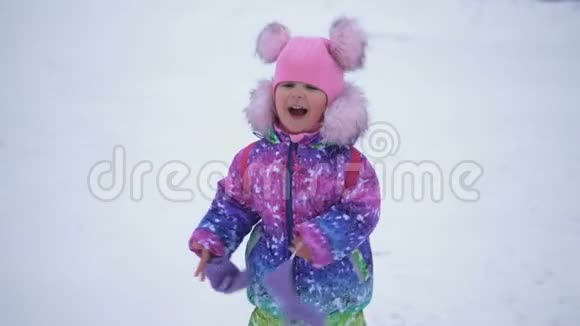 快乐可爱的小女孩在雪地里奔跑慢动作视频的预览图