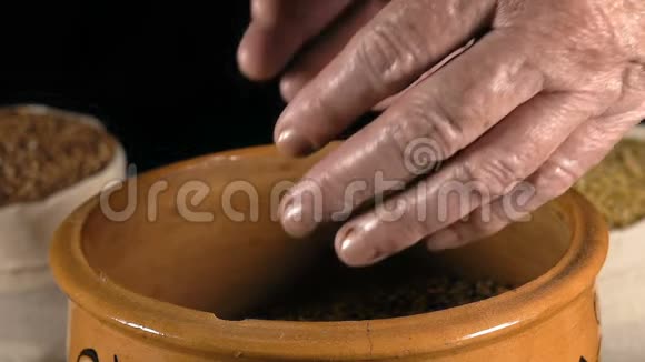 特写慢镜头老妇人的手从陶罐里拿出麦粒手拿麦粒视频的预览图