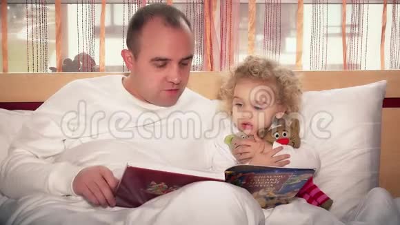 小女儿和爸爸坐在床上看书视频的预览图