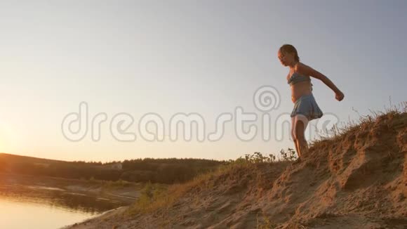 一个快乐的小女孩在蓝天的沙滩上跳跃视频的预览图