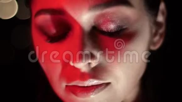 漂亮的女性脸的特写镜头带有诱人的妆容红色霓虹灯和bokeh背景摆在面前视频的预览图