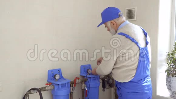 老人在蓝色工作服中修理暖气管道视频的预览图