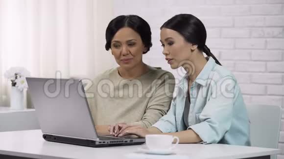 女孩教妈妈使用笔记本电脑显示有用的软件电脑识字视频的预览图