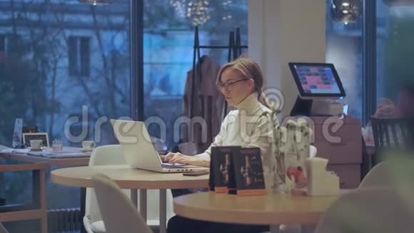晚上女孩坐在一家舒适的咖啡馆里使用笔记本电脑视频的预览图
