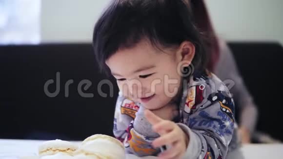 一个可爱可爱的亚洲幼儿男孩喜欢和他的母亲坐在他身边吃马卡龙视频的预览图