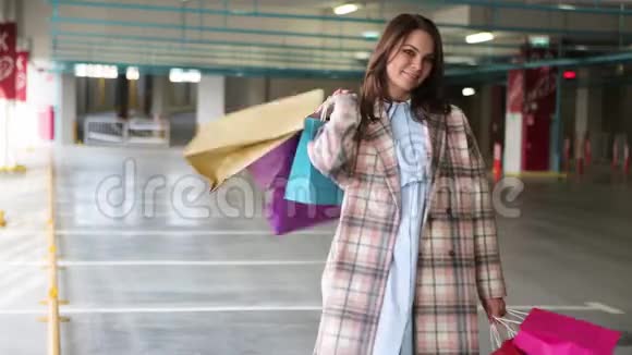 带包的年轻女人购物后很高兴深色的女人在商店旁边有多种颜色的包裹出售视频的预览图